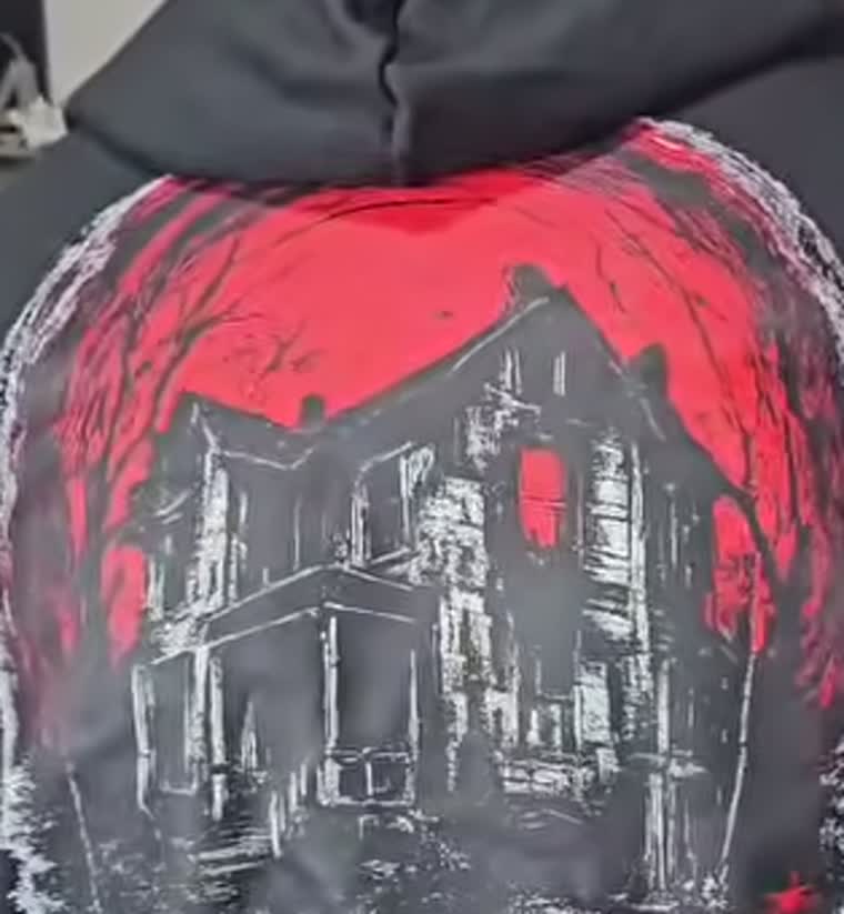 Costas do moletom, com a estampa do casarão assombrado sob um céu vermelho